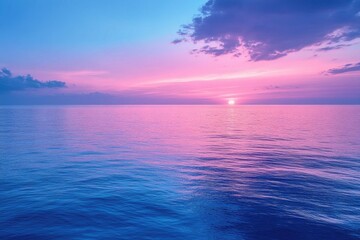 Obraz premium Pink sunset over ocean with blue water and soft clouds on the horizon. Use for peaceful, calming themes; travel blogs or nature photography.