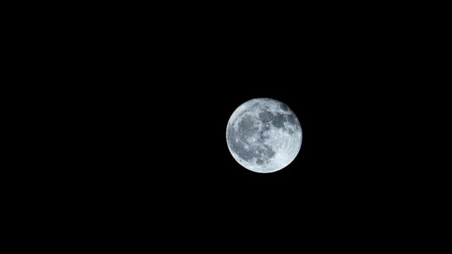 The full moon rises and crosses a black sky with no clouds in this lunar time lapse