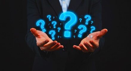 Person in suit holding glowing blue question marks floating above their open palms in a dark setting