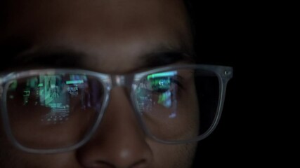 Adult Indian man smartphone user with eyeglasses doomscrolling through social media reels in dark room, Closeup of eyes