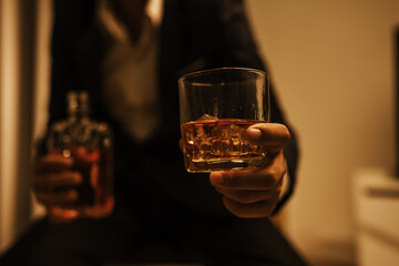 A stylish man holds a glass of whiskey at an upscale bar, enjoying a luxurious indoor celebration with friends and fine alcohol.