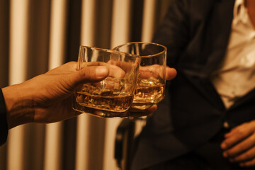A stylish man holds a glass of whiskey at an upscale bar, enjoying a luxurious indoor celebration with friends and fine alcohol.