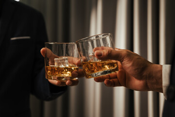 A stylish man holds a glass of whiskey at an upscale bar, enjoying a luxurious indoor celebration with friends and fine alcohol.