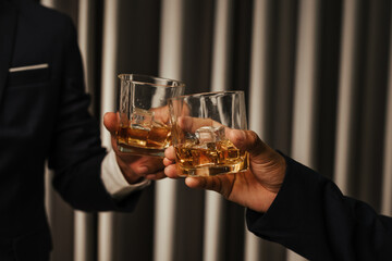A stylish man holds a glass of whiskey at an upscale bar, enjoying a luxurious indoor celebration with friends and fine alcohol.