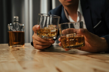 A stylish man holds a glass of whiskey at an upscale bar, enjoying a luxurious indoor celebration with friends and fine alcohol.