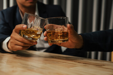 A stylish man holds a glass of whiskey at an upscale bar, enjoying a luxurious indoor celebration with friends and fine alcohol.