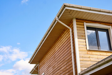 wooden house facade with modern window under clear blue sky. bright and sunny day showcasing contemporary architecture and sustainable living in suburban neighborhoods.