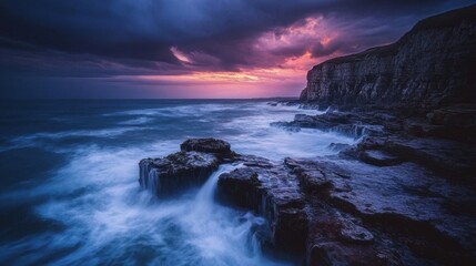 Obraz premium Stormy Ocean Waves Crash on Rocky Shoreline at Sunset with Dramatic Purple Sky