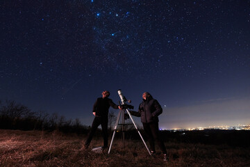 Amateur astronomers using telescope for watching stars, Moon, planets and other celestial objects from a field in nature.