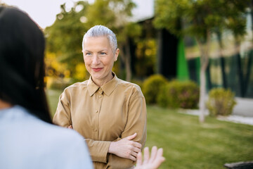 Businesswoman engages in discussion outdoors with a colleague during late afternoon in a modern...