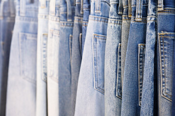 A close up of a blue denim row of jeans hanging on a rack. of different colors and styles. Concept of variety and choice.