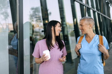 Nurses engaging in friendly conversation outside a modern healthcare facility during the day
