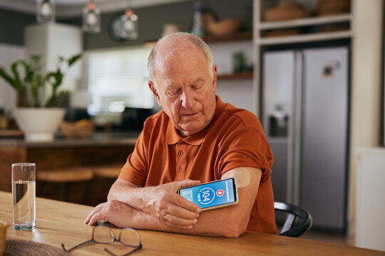 Senior man checking blood sugar level with smartphone