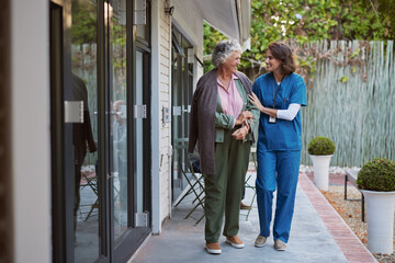 Nurse assisting senior woman at nursing home while walking