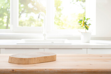 Wood podium board on wooden kitchen table over blurred sink against window interior background