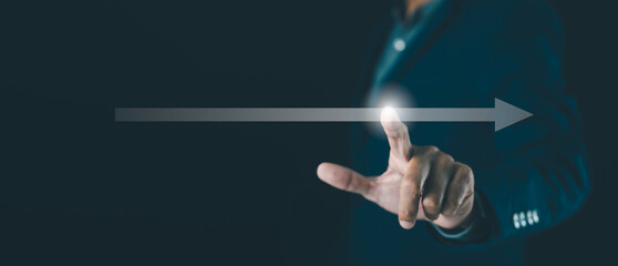 A person in a suit touches a glowing arrow on a dark background, symbolizing progress, direction, and technology.