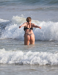 Fototapeta premium A woman in a bikini is in the ocean, splashing water