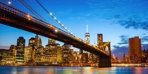 Brooklyn Bridge connecting Manhattan at dusk with One World Trade Center rising above New York City skyline