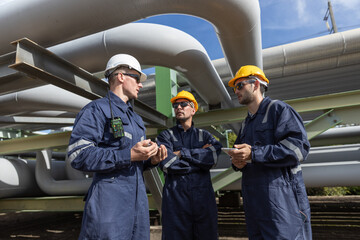 Three engineers engage in a discussion about pipeline maintenance procedures at an industrial site....