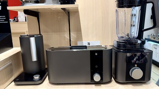 Cookware and appliance store display featuring premium WMF set with electric kettle, toaster, and blender in foreground..