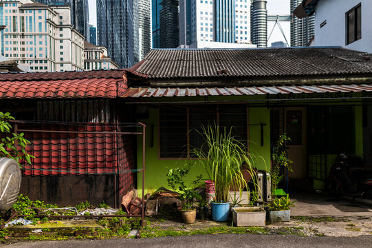 Metal roofed house with lush pots under Kuala Lumpur highrise downtown, Malaysia