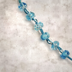 textured stylish old paper background, square, with a simple necklace of blue and transparent glass...