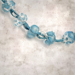 textured stylish old paper background, square, with a simple necklace of blue and transparent glass...