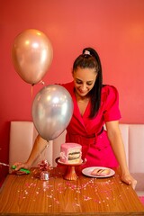 Plakat Woman celebrating with a pink cake and balloons.