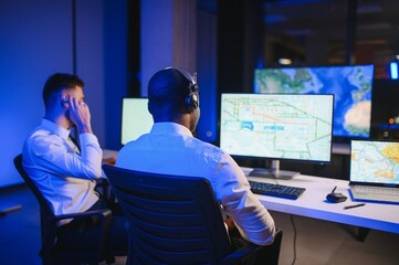 Center of dispatching maintenance. Portrait of men working via headset microphone while sitting on...
