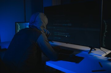 Hacker with computer, man sitting at a table in a hoody