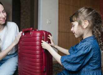 Tired mother with 6 year old daughter packing travel suitcase. Travel concept. Close-up of travel bag and tired faces of travelers.
