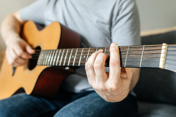 Man sitting and playing guitar, strumming chords, learning to play. Hobbies for adults