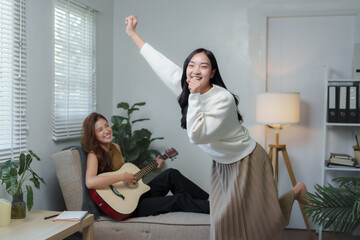 Plakat Young women playing guitar and dancing at home