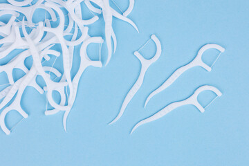 Dental floss picks on blue background. Soft floss picks. Dental picks. Plastic white dental toothpick with floss