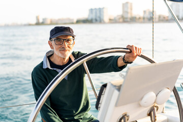 Experienced sailor steering yacht on calm waters