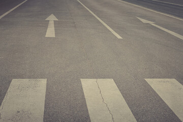 Guiding lines on an empty street stretch toward the horizon under a cloudy sky at dusk