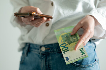 Close-up of person holding smartphone and 100 euro, symbol of online income and freelance earnings