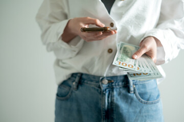 Close-up of person holding smartphone and cash dollars, symbol of online income and freelance earnings