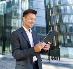 Business professional engaged in digital communication outside modern urban office building