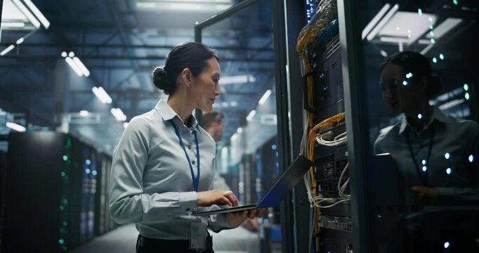 Data Center: Asian Female Programmer Using Laptop Computer, Smiling while Inputting Data. Cloud Computing Server Farm System Administrator Working on IT Maintenance for Saas Business Company