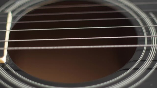 Close-up of buzzing vibrating strings on an untuned guitar, guitar tuning concept, string instrument sound