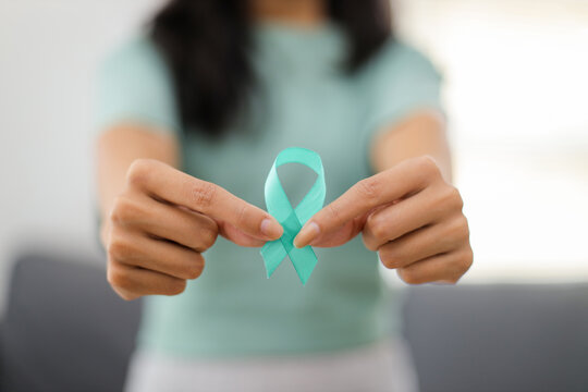 Woman Holds Teal Ribbon. Symbolic for Cervical Cancer, Ovarian Cancer, Gynecological Cancer and PCOS