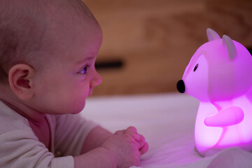 A Baby's Curious Gaze: A baby gazes at a soft, glowing fox nightlight with an expression of wonder...