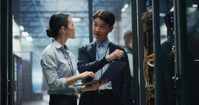 In a Modern Data Center, Asian Male Data Scientist and Female AI Specialist Analyze Algorithms on a Laptop Computer. Specialists Exploring Machine Learning Models for Large Language Models