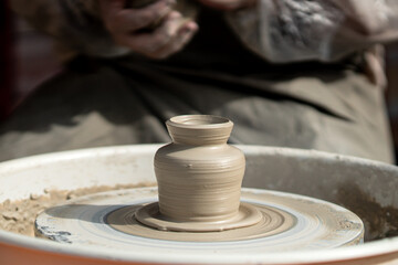 Hands of male potter, ceramist making of an earthenware pot. Potter make a pitcher on a pottery wheel.