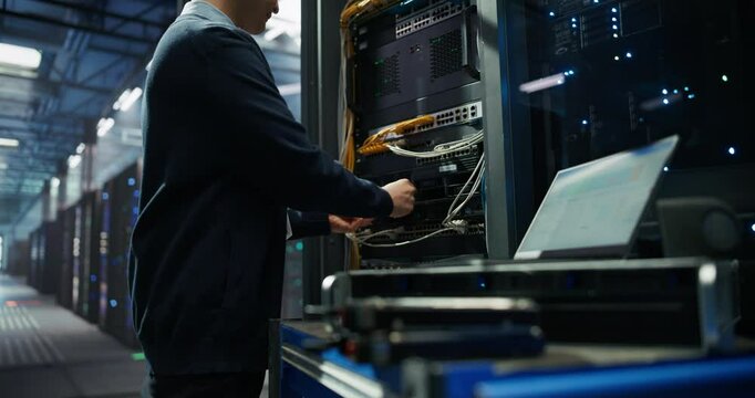 Male IT Technician Working with Server Racks in a Modern Data Center. Providing Maintenance Work and Installing New Hardware for Database and Storage Hard Drives for AI Model Training and Compute