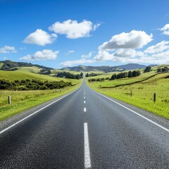 Fototapeta premium Asphalt road stretches into distance under blue sky with clouds aerial perspective in New Zealand countryside