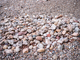 Close-up of multicolored stones and gravel on the shore of Liptovská Mara in Slovakia. Natural texture background with rounded pebbles and fine rock.