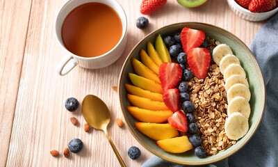 Top view of healthy breakfast with fresh fruits, granola, and yogurt on table in bright natural light, clean and minimal composition