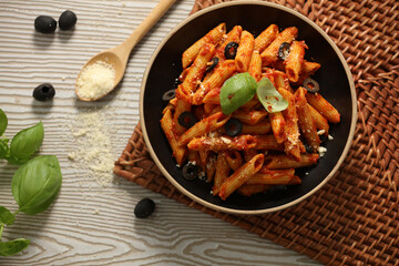 Pasta with simple tomato sauce with black olives, top view with raw mat